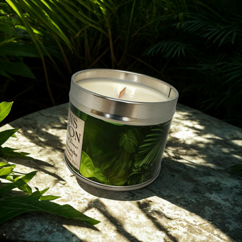 Candle in a tin with green leaves on a stone surface surrounded by plants