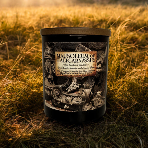 Candle labeled 'Mausoleum of Halicarnassus' in a grassy field with ruins in the background