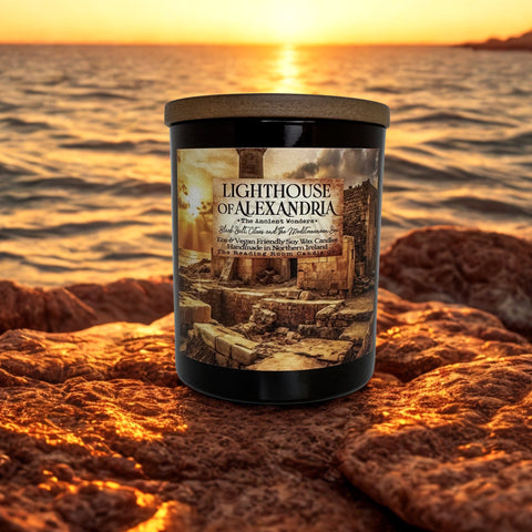 Candle labeled 'Lighthouse of Alexandria' on a rocky shore with sunset in the background