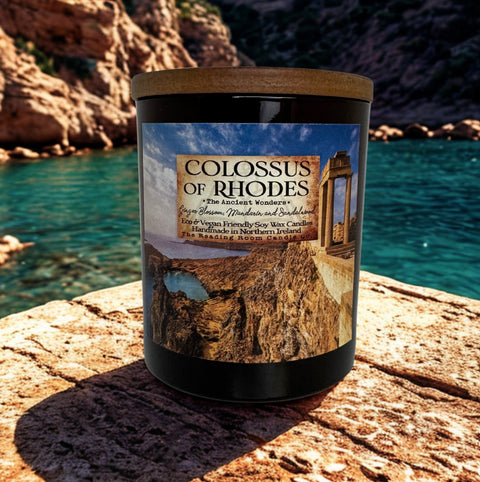 Candle labeled 'Colossus of Rhodes' on a rocky surface with a scenic background