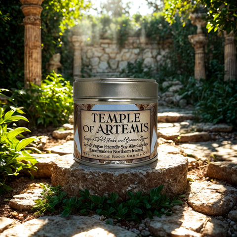 Candle tin labeled 'Temple of Artemis' on a stone surface with greenery in the background