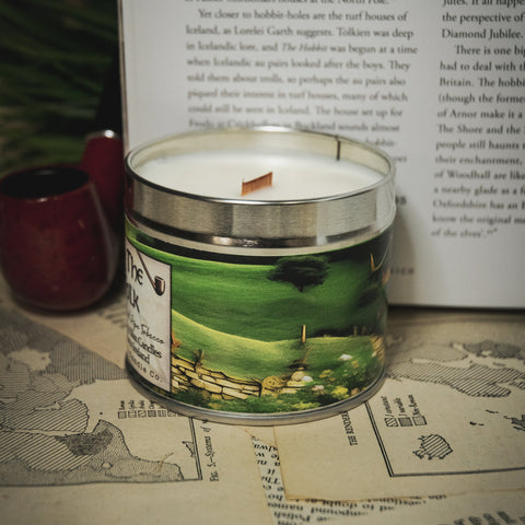 Soy Wax Candle labeled 'Home of the Half Folk' on a table with an open book 