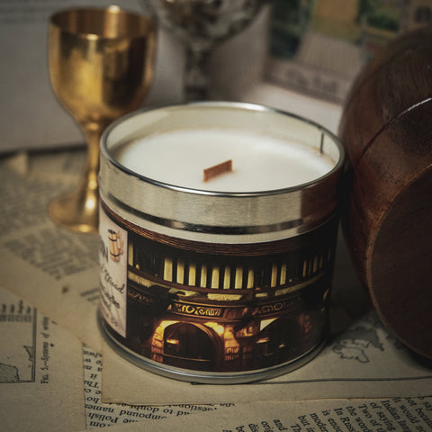 Soy Wax Candle tin labeled 'The Old Dragon Tavern' on a surface with a blurred bookish background