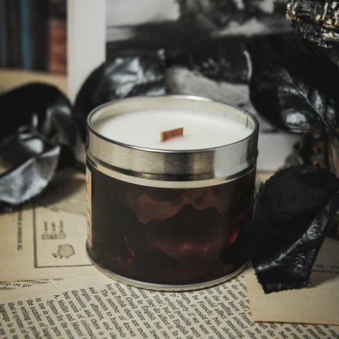Soy Wax Candle tin labeled 'The Shadow Lands' on an open book with a dark, moody background.