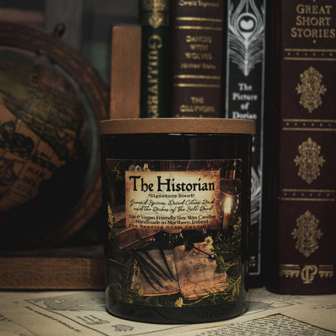 soy wax candle abeled 'The Historian' with vintage books and a globe in the background