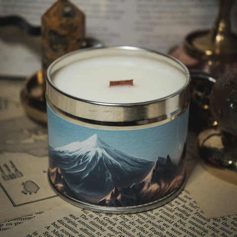 Candle in a tin with mountain design on a surface with text