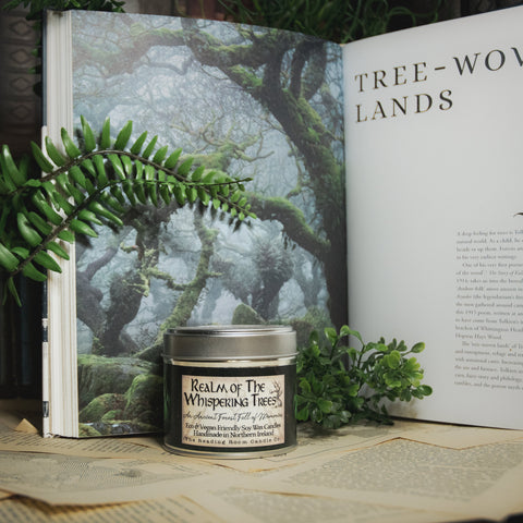 Soy Wax Candle labeled 'Realm of the Whispering Trees' on a surface with a forest-themed background.