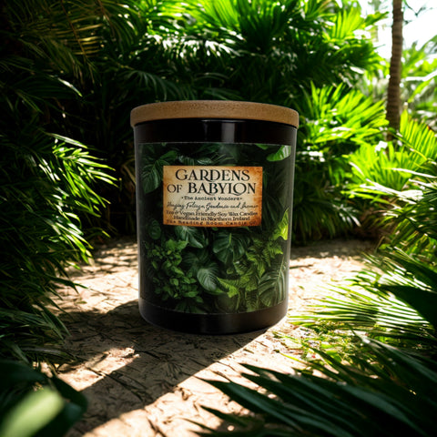 Candle labeled 'Gardens of Babylon' surrounded by green foliage