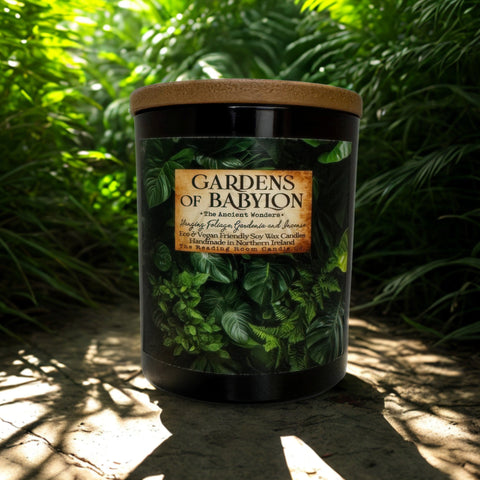 Garden-themed candle labeled 'Gardens of Babylon' in a natural setting with greenery.